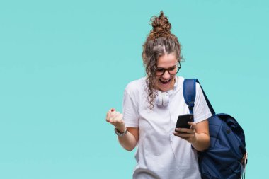 Sırt çantası, kulaklık ve akıllı telefon gurur çığlık ve zafer ve başarı çok heyecanlı, kutluyor izole arka plan üzerinde giyen genç esmer öğrenci kız duygu tezahürat