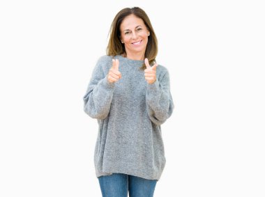 Güzel orta yaş kadın, mutlu ve komik yüz ile kamera parmaklar işaret izole arka plan üzerinde kış kazak giyiyor. İyi enerji ve Vibes.