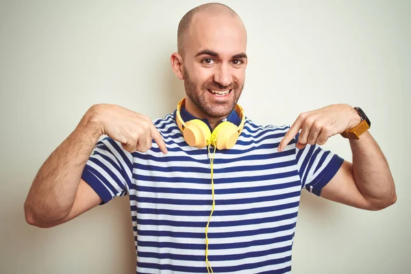孤立した背景の上に黄色のヘッドフォンを着用して音楽を聴いている若い男は 顔に笑顔で自信を持って見て 誇りと幸せな指で自分自身を指差す — ストック写真