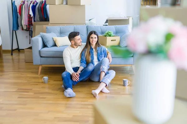 Yeni bir daire zemin üzerinde oturan genç güzel çift, yeni bir eve taşınmak için mutlu sevgi gülümsüyor