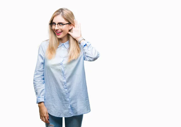 stock image Young beautiful blonde business woman wearing glasses over isolated background smiling with hand over ear listening an hearing to rumor or gossip. Deafness concept.