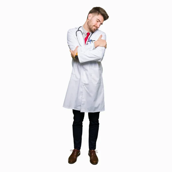 Young Handsome Doctor Man Wearing Medical Coat Hugging Oneself Happy — Stock Photo, Image