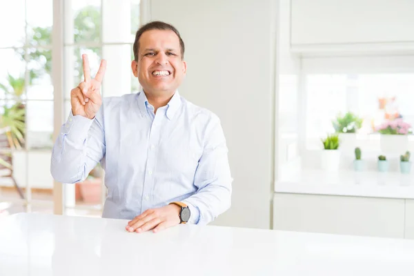 家に座っている中年の男性は 自信を持って幸せに微笑んでいる間 2番の指を示す — ストック写真