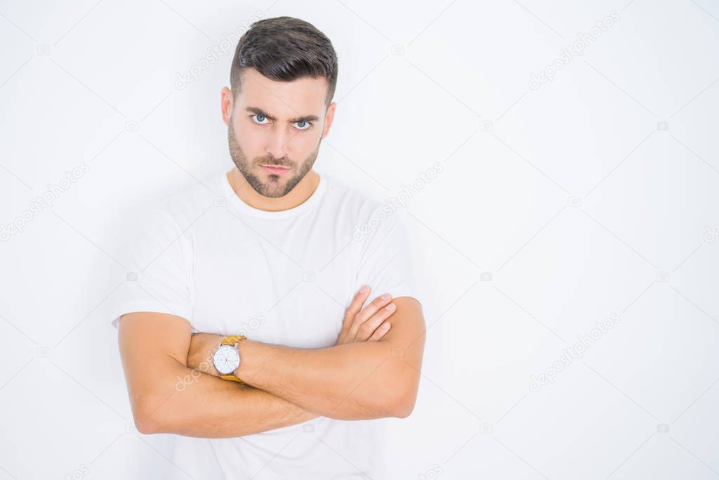 Young handsome man wearing casual white t-shirt over white isolated background skeptic and nervous, disapproving expression on face with crossed arms. Negative person.
