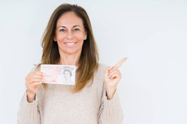 Orta yaş kadın izole arka plan üzerinde 50 lira banka notu tutan çok mutlu yan el ve parmak ile işaret