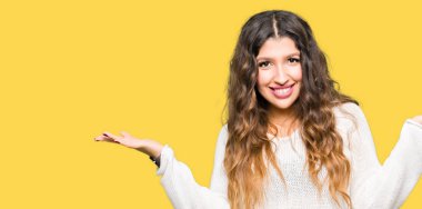 Eller beyaz kazak gülen gösteren her iki giyen genç güzel kadın açık avuç içi, sunmak ve reklam karşılaştırma ve denge