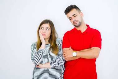 Beyaz izole arka plan üzerinde genç güzel çift birlikte yorgun görünümlü ve çapraz kolları ile depresyon sorunları ile sıkılmış düşünme.