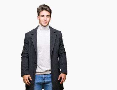 Seksi bir ifadeyle, neşeli ve mutlu yüzünü kameraya bakarak göz kırpıyor izole arka plan üzerinde kış ceket giyen genç zarif adam.