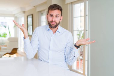 Yakışıklı iş adam clueless ve şaşkın bir ifadeyle kollar ve eller kaldırdı. Şüphe kavramı.