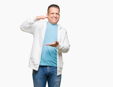 Üzerinde sweatshirt giyen orta yaş Arap adam arka plan ile büyük ve büyük boy işaret, ölçü birimi sembol gösteren el eller izole. Kameraya bakarak gülümsüyordu. Ölçüm kavramı.