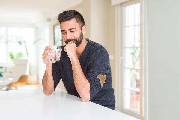 stock image Handsome hispanic man drinking a fresh glass of water serious face thinking about question, very confused idea