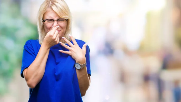 若い美しい金髪女性の臭いと嫌な何かの臭いがする分離の背景 耐え難い臭い 鼻に指を使って保持息でメガネを着用します 悪いにおいの概念 — ストック写真