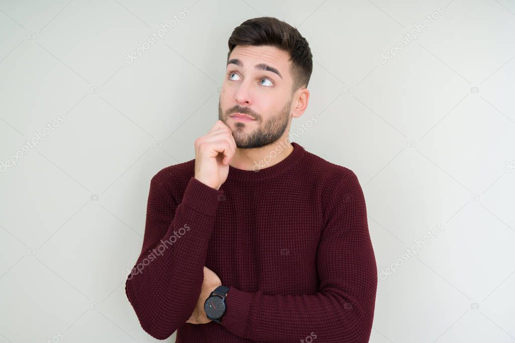 Young handsome man wearing a sweater over isolated background with hand on chin thinking about question, pensive expression. Smiling with thoughtful face. Doubt concept.