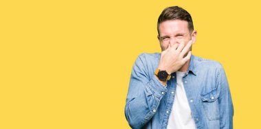 Bir şey pis ve iğrenç kokulu denim ceket, dayanılmaz koku, holding nefes parmak ile burun üzerinde giyen sakal ve mavi gözlü yakışıklı adam. Kötü kokuyor kavramı.