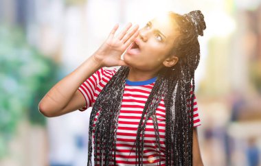 Genç örgülü saç Afro-Amerikan Kız bağırarak ve ağzı üzerinde el ile yan için çığlık izole arka plan üzerinde. İletişim kavramı.