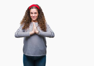 Ellerle birlikte AF emin gülümseyen için soran dua izole arka plan üzerinde kazak giyen güzel esmer kıvırcık saçlı Genç kız çizgili.