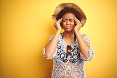 Beyaz izole arka plan üzerinde yaz şapkası giyen afro saçlı genç afro-amerikalı kadın baş ağrısı umutsuz muzdarip ve stresli çünkü ağrı ve migren. Eller baş üstünde.