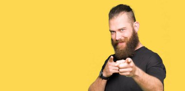 Genç sarışın adam rahat t-shirt giyen mutlu ve komik yüzü ile kameraya parmakları işaret. İyi enerji ve titreşimler.