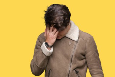 Genç yakışıklı adam üzgün ifade yüz eller ile ağlayarak süre kapsayan ile izole arka plan üzerinde kış palto giyiyor. Depresyon kavramı.
