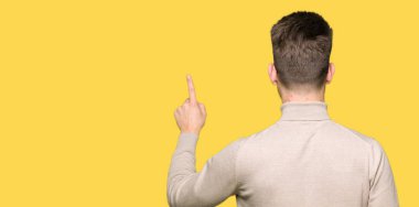 Geriye doğru arkasında parmak eliyle işaret Posing giyen genç yakışıklı iş adamı gözlük