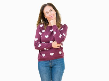 Üzerinde kalpler kazak giyen güzel orta yaş kadın arka plan çene düşünme hakkında soru, dalgın ifade üzerine el ile izole. Düşünceli yüzüyle gülümsüyor. Şüphe kavramı.