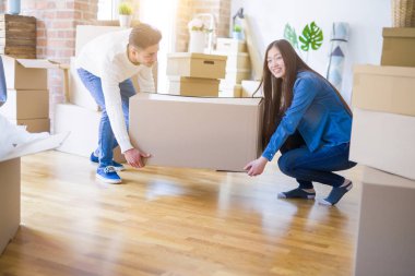 Güzel genç Asyalı Çift mutlu görünümlü, yeni bir eve hareket heyecanlı gülümseyen büyük bir karton kutu tutarak