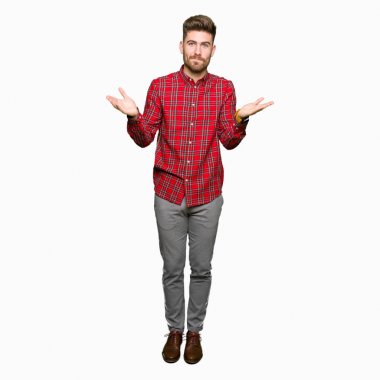 Yakışıklı delikanlı clueless ve şaşkın bir ifadeyle kollar ve eller kaldırdı. Şüphe kavramı.