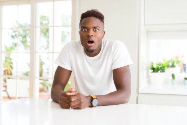 Afro-Amerikan yakışıklı beyaz tablo evde korkuyor ve sürpriz ifade ile şok korku ve yüz heyecanlı.