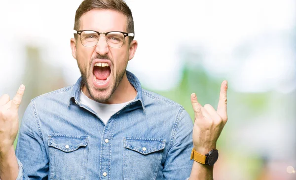 ハンサムな男が眼鏡を手でロックのシンボルをやって狂った表情で叫ぶ 音楽の星 重いコンセプト — ストック写真