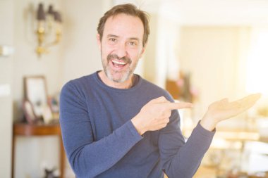 Yakışıklı orta yaş el ile sunulması ve parmak ile işaret ederken evde şaşırdım ve kameraya gülümseyen adam.