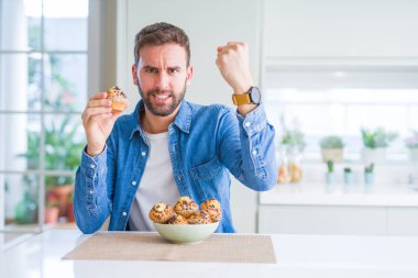 Yakışıklı adam çikolata kek yeme rahatsız ve boşa çıkarmak ile öfke, çılgın da yükseltilmiş el ile bağırmaya kavramı öfke