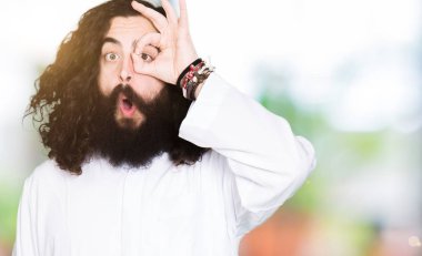 Sürpriz yüz, göz parmaklarının arasından seyir ile ok jest yapıyor Tanrı aşkına giyinen adam şok. İmansız ifade.