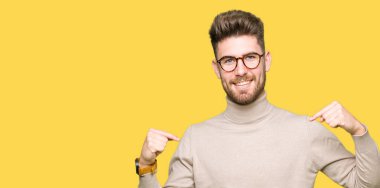 Yüzünde gülümseme ile kendinden emin görünüyorsun, kendini gururlu ve mutlu parmakları ile işaret gözlüklü genç yakışıklı iş adamı.