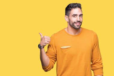 Yakışıklı delikanlı arıyor ve başparmak yanında yukarıyı mutlu yüz ile gülümseyen izole arka plan üzerinde.