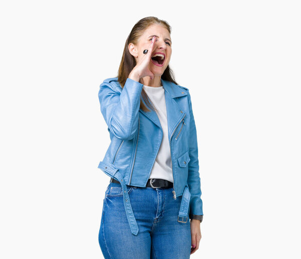 Beautiful middle age mature woman wearing fashion leather jacket over isolated background shouting and screaming loud to side with hand on mouth. Communication concept.