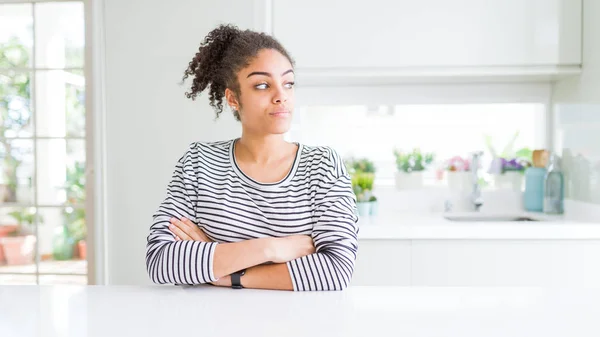 Beautiful african american woman with afro hair wearing casual striped sweater looking to the side with arms crossed convinced and confident