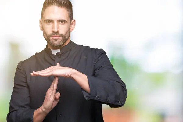 Young Christian priest over isolated background Doing time out gesture with hands, frustrated and serious face