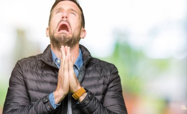 Yakışıklı adam yalvarıyor ve umut ifade yüzünde çok duygusal ve endişe ile birlikte elleriyle dua kış palto giyiyor. Bağışlanmak. Din kavramı.