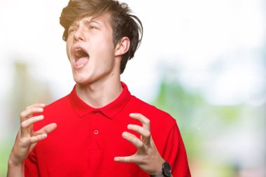 Genç yakışıklı adam izole arka plan üzerinde kırmızı t-shirt giyiyor çılgın ve deli çığlık ve agresif ifade ve silah ile bağırdı kaldırdı. Hayal kırıklığı kavramı.