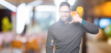 Yakışıklı delikanlı yapıyor gülümseyen izole arka plan üzerinde gözlük telefon hareketi ile el ve parmak telefonda konuşuyor gibi. Kavramları iletişim.