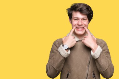 Genç yakışıklı adam giyen kış ceket izole üzerinde arka plan gülen açık ağız ile parmak işaret ve neşeli gülümseme zorlamadan