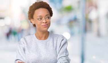 Genç güzel Afrikalı-Amerikalı kadın görünümlü yan ve dik dik bakma uzağa düşünce gülümseyen izole arka plan üzerinde gözlük.