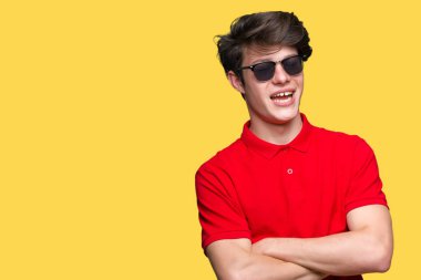 Yakışıklı delikanlı üzerinde güneş gözlüğü takıyor mutlu yüz ile gülümseyerek kameraya seyir silah geçti arka plan izole. Olumlu bir kişi.