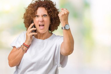 Orta ager üst düzey kadın smartphone üzerinde izole arka rahatsız ve öfke, çılgın ve yükseltilmiş eliyle diye bağıran ile sinirli bağırarak öfke kavramı söz