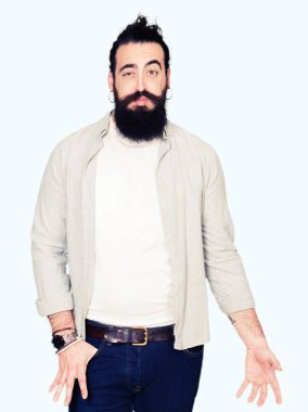 Uzun saç, sakal ve komik surat ile yanakları şişirme küpe olan genç adam. Ağız ile hava, deli ifade şişirilmiş.