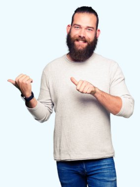 Casual kazak giyen genç sarışın adam kendinden emin gülümseyen arkasından el ve kadar başparmak ile işaret