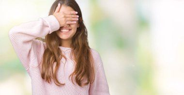 Gülümsüyor ve gözleri için sürpriz kapsayan yüz el ile gülüyor izole arka plan üzerinde pembe kış kazak giyen genç güzel esmer kadın. Kör kavramı.