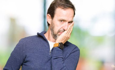 Orta yaş yakışıklı adam bir kazak giyen yorgun görünümlü ve çapraz kolları ile depresyon sorunları ile sıkılmış.