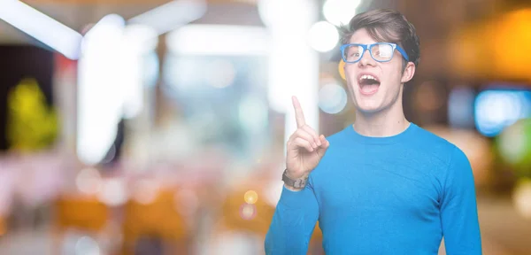 Jonge Knappe Man Een Blauwe Bril Geïsoleerde Achtergrond Wijzende Vinger — Stockfoto