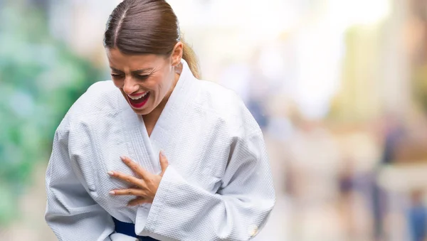 Young beautiful woman wearing karate kimono uniform over isolated background with hand on stomach because nausea, painful disease feeling unwell. Ache concept.
